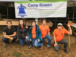 Jordan, Jessica, Jocelyn, Aedan, and Alex kneeling in front of the Camp Bowen banner with the Showdown table in the background.