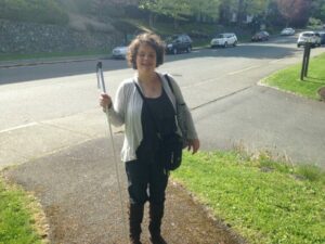 A blind woman walking independently with her long white cane.