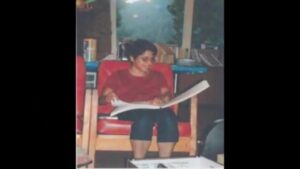 A girl sitting in a chair, reading a Braille book